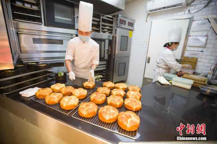 资料图:2月20日,山西太原一面包店,糕点师正在制作糕点。山西餐饮业商家通过线下门店民众进门量体温、消毒、留联系方式,线上外卖配送等多种方式积极防控疫情,逐步开始复工。 中新社记者 张云 摄 中国饭店协会:现金流成餐企最大问题,但未来可期
