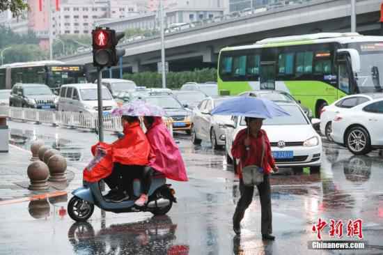 资料图:市民冒雨出行。中新社记者 贾天勇 摄 江南华南有持续性强降水 华北黄淮有持续性高温天气