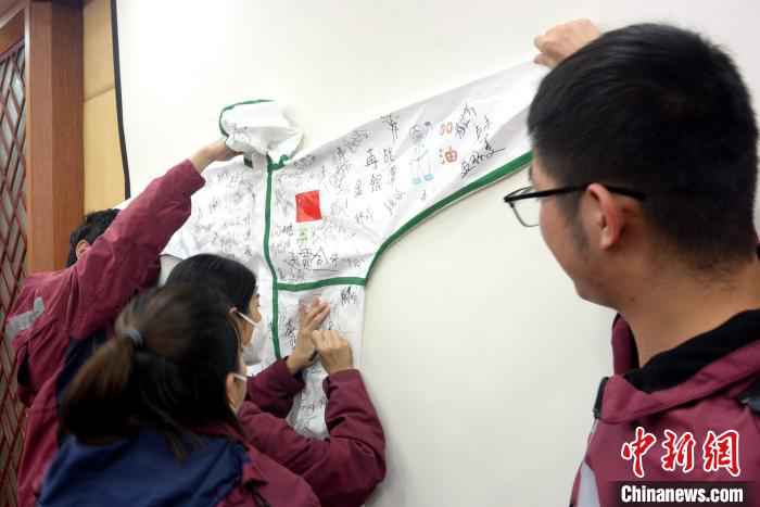 支援湖北医疗队员在防护服上签名、写祝福,留下纪念。 龚雯 摄 福建漳州首批驰援湖北医疗队凯旋:想念家乡味道
